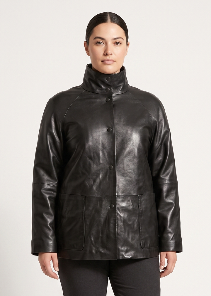 A model stands against a light gray studio background wearing a black leather jacket with a high collar, black trousers, and black boots.